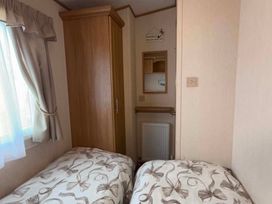 A bedroom with two beds and a wardrobe at Happy Days Caravan Park - Holiday Accommodation 3599 Towyn