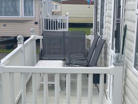 An outdoor area with chairs and a table at Happy Days Caravan Park - Holiday Accommodation 3599 Towyn