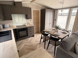 A kitchen with an oven and dining table at Berwick Holiday Park - Holiday Accommodation 37, Berwick-upon-Tweed