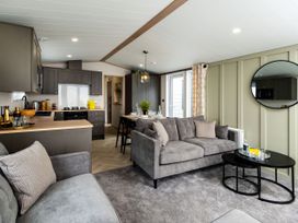 A living room with a sofa and kitchen area at Perran Sands - Holiday Accommodation 4301 Perranporth