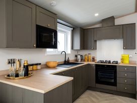 A kitchen with cabinets, microwave, sink, and stove at Perran Sands - Holiday Accommodation 4301 Perranporth