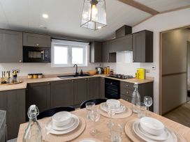 A kitchen with appliances and dining table at Perran Sands - Holiday Accommodation 4301 in Perranporth