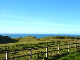 A view of hills and sea with a wooden fence at Perran Sands - Holiday Accommodation 4301, Perranporth