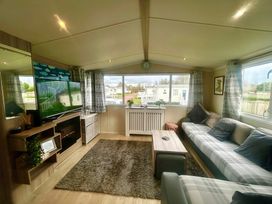 A living room with a television and sofa at 62 Snowdonia View, Hafan y Mor Haven - 4345 Pwllheli