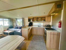 A kitchen and living room area with a sofa and dining table at 62 Snowdonia View, Hafan y Mor Haven - 4345 Pwllheli