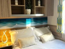 A bedroom with a bed and decorative pillows at 62 Snowdonia View, Hafan y Mor Haven - 4345 Pwllheli