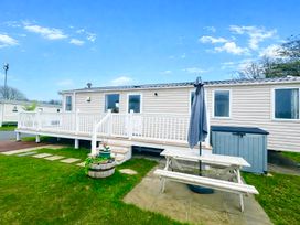 An outdoor area with a mobile home, deck, table with umbrella, and storage unit at 62 Snowdonia View, Hafan y Mor Haven - 4345 Pwllheli