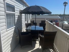 An outdoor seating area with a table and chairs under an umbrella at Golden Sands Kinmel Bay - Holiday Accommodation 4446, Rhyl