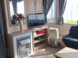 A living room with a television, heater, and sofa at Towervans Holiday Park - Holiday Accommodation 5041, Mablethorpe