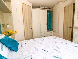 A bedroom with a bed and wardrobe at Beachcombers in Wareham