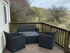 An outdoor seating area with a sofa and armchairs at Perran Sands - Holiday Accommodation 722 Perranporth