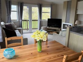A living room with a dining table and flowers at Perran Sands - Holiday Accommodation 722 Perranporth