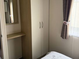 A bedroom with a wardrobe and mirror at Perran Sands - Holiday Accommodation 722 Perranporth