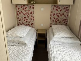 A bedroom with two beds and a bedside table at Perran Sands - Holiday Accommodation 722 in Perranporth
