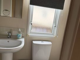 A bathroom with a sink, toilet, and window at Perran Sands - Holiday Accommodation 722 Perranporth