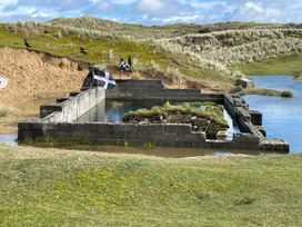 A stone structure in water with flags at Perran Sands - Holiday Accommodation 722 Perranporth