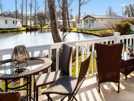 A table and chairs on a balcony overlooking a pond at Haggerston Castle - Holiday Accommodation 779 Berwick-upon-Tweed