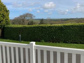 A view from a fenced outdoor area with a hedge and lamp post at White Acres Holiday Park - Holiday Accommodation 8002 Newquay