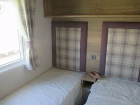 A bedroom with twin beds and a window at Durdle Door Holiday Park - Holiday Accommodation 8299 Wareham