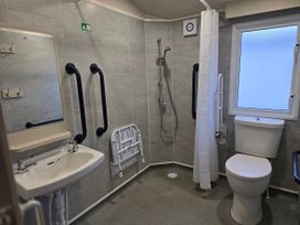 A bathroom with a sink, toilet, shower, and grab rails at Golden Sands - Holiday Accommodation 8309 Mablethorpe