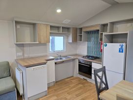 A kitchen with a sink stove fridge and cabinets at Golden Sands - Holiday Accommodation 8309 Mablethorpe