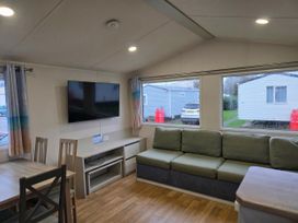 A living room with a television and sofa at Golden Sands - Holiday Accommodation 8309 in Mablethorpe