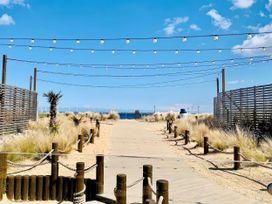 A boardwalk leading to the beach with string lights and palm trees at Seashore Holiday Park - Holiday Accommodation 848 Great Yarmouth