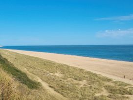 A beach with sand and grass near the ocean at Green Farm Caravan Park - Holiday Accommodation 9807 Scratby, Great Yarmouth