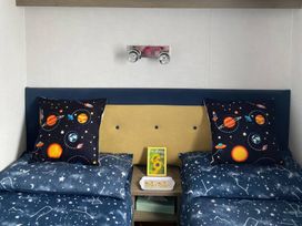 A bedroom with two beds and space-themed pillows at Primrose Valley Holiday Park - Holiday Accommodation 9833, Filey
