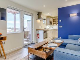 A living room with a sofa and kitchen area at Lakeside Studio in Portreath