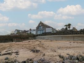 A beach with a house and palm trees at The Boat House - Port Eynon