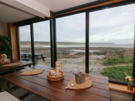 A dining room with a table and chairs overlooking the coast at The Boat House - Port Eynon