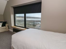 A bedroom with a bed and a window view at The Boat House - Port Eynon