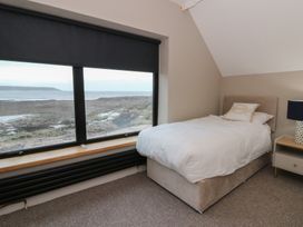 A bedroom with a bed and a window overlooking the sea at The Boat House - Port Eynon