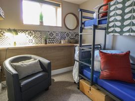 A bedroom with bunk bed and chair at The Boat House - Port Eynon