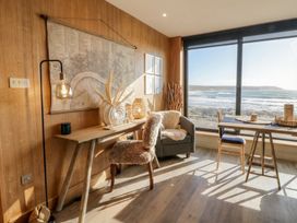 A living room with a table and chair near a window at The Boat House - Port Eynon