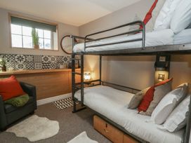 A bedroom with a bunk bed and sofa at The Boat House - Port Eynon