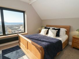 A bedroom with a bed and a large window at The Boat House - Port Eynon