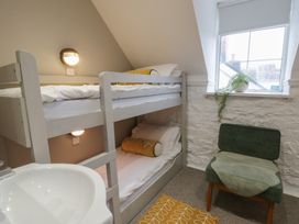 A bedroom with a bunk bed and a chair at The Boat House - Port Eynon