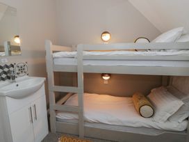 A bunk bed with white linens and a sink in a bedroom at The Boat House - Port Eynon