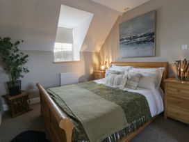 A bedroom with a bed, nightstands and a plant at The Boat House - Port Eynon