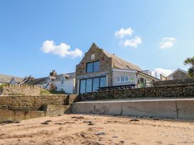 A building near the beach with a stone wall at The Boat House - Port Eynon
