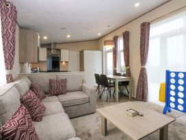 A living room with a sofa and dining area at Blue Skies in Caernarfon