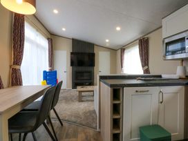 A living room with a dining area and kitchen appliances at Blue Skies in Caernarfon