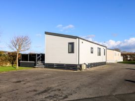 A mobile home with exterior steps and a parking lot at Blue Skies near Caernarfon