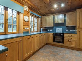 A kitchen with wooden cabinets and appliances at Kinder Lodge (Pet) Fowlis near Dundee