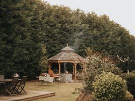 A gazebo in a garden with seating and trees at Garden Pod in Waltham