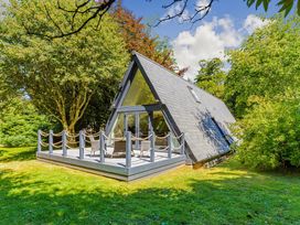 A house with a deck and chairs surrounded by trees at St Ives Studio in Praze-An-Beeble