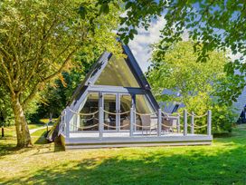 A house with a deck and chairs surrounded by trees at St Ives Studio in Praze-An-Beeble