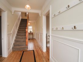 A hallway with a staircase and coat hooks at The Manse in Whitby
